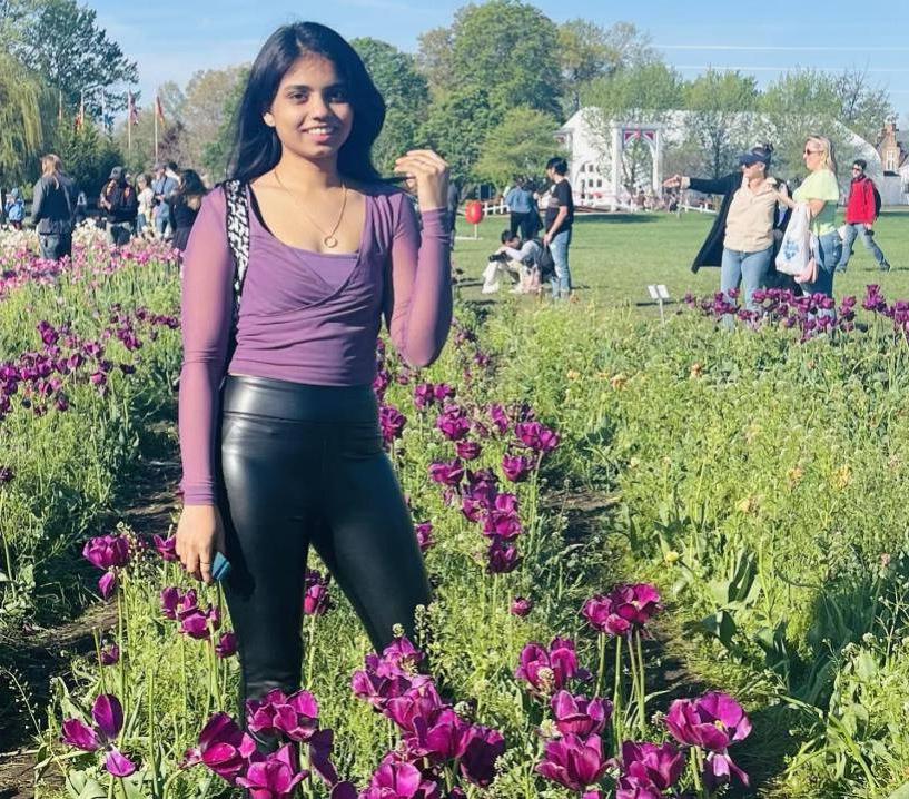 Woman smiling at camera, standing amongst purple tulips